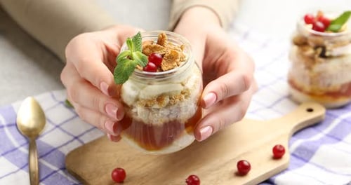 Femme avec un délicieux dessert bagatelle dans un bocal en verre à table, gros plan