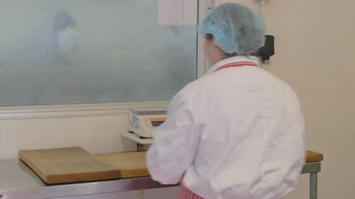 Female factory employee making butter with wooden tools