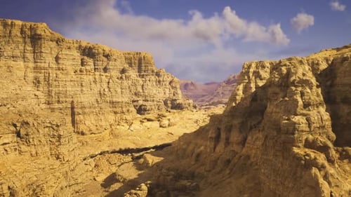 Sunlight Emphasizes Stratified Rocks and Scattered Stones in Canyon