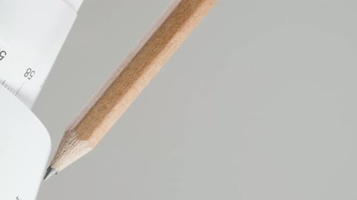 Crayon et règle en papier, enroulée, avec des marques centimétriques, sur fond blanc. Thème de construction,