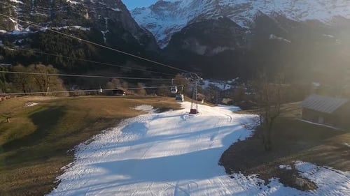 Spring Skiing Gondola Over Patchy Snowfield in Sunlit Alpine Valley