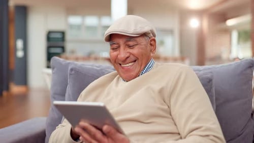 Smiling Senior Man Using Tablet on Sofa at Home