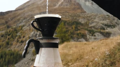 Traveler Man Making Filter Coffee and Pours Water in Ground Coffee Beans Against Mountain View