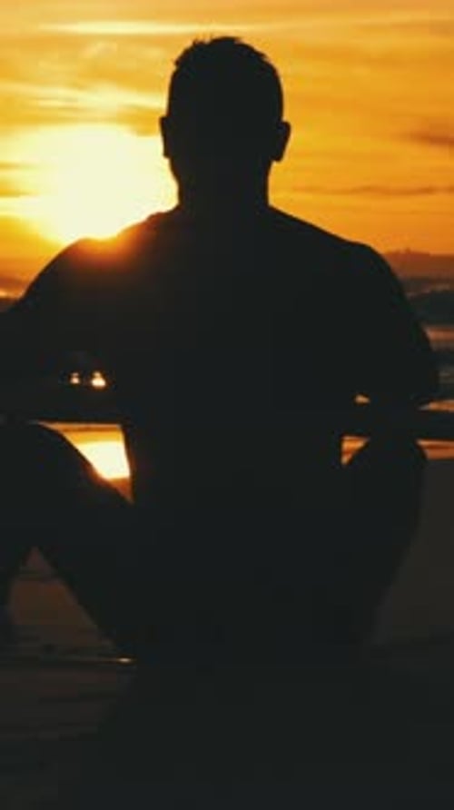 Man Meditating on Beach at Sunrise in Silhouette