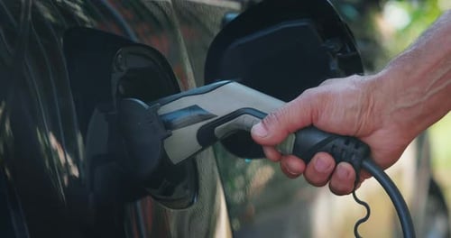 Slow motion close up of power supply plugged into an electric car for charging a modern battery wh