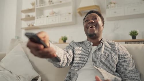 Man Smiling, Watching TV on the Couch