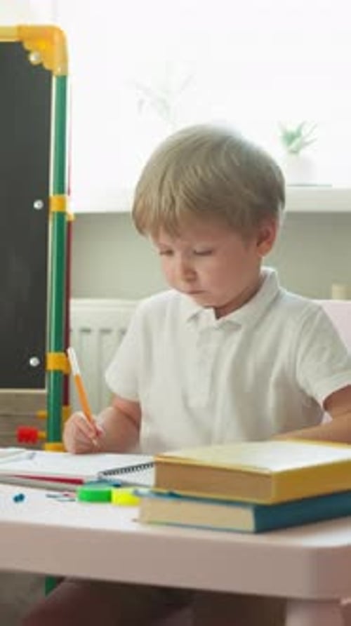 Child Draws with Pencil at Table Indoors