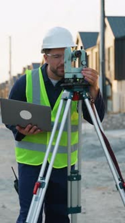 Surveyor Engineer Using Theodolite and Laptop on Construction Site
