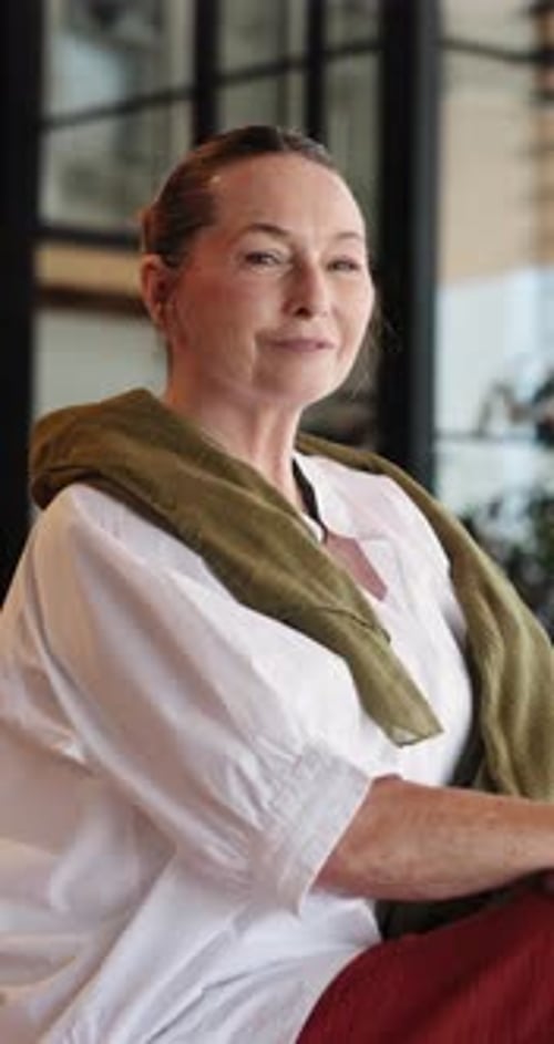 Smiling Mature Woman Seated Indoors Looking Away