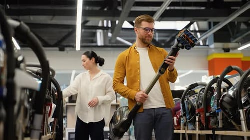 Just Married Couple Choosing Vacuum Cleaner in an Electronics Store for New Home