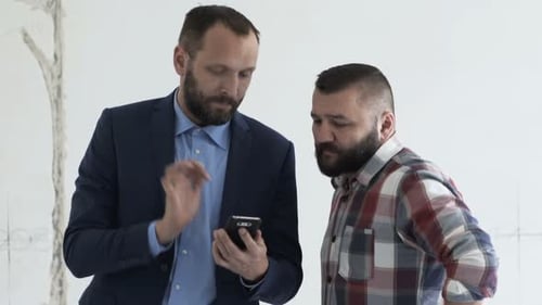 Real estate agent and client discussing new home project using smartphone