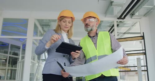 Woman manager in hardhat inspecting house or office together with professional contractor