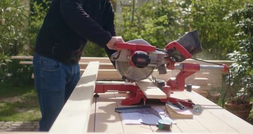 Man Cuts Wood with Miter Saw Outdoors