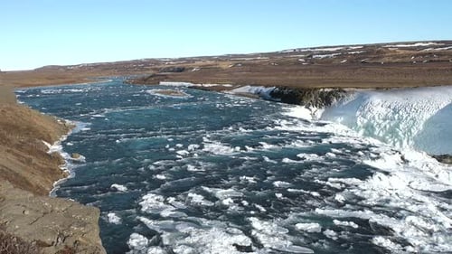 Majestätischer Wasserfall, der über felsige Klippen in einer Winterlandschaft kaskadiert.