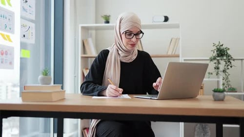 Woman in Hijab Making Notes From Laptop Screen in Office
