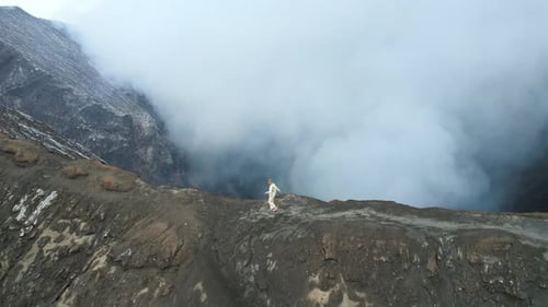 Epic Aerial View of Woman Runs Along the Edge of the Steaming Crater of Volcano