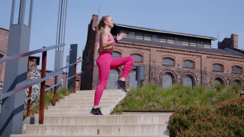 Slim young woman runs in place and does jumping jacks outdoors, slo-mo