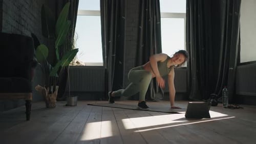 Junge Hausfrau trainiert morgens zu Hause, Dame in Sportkleidung trainiert für eine gute Körperform