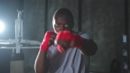 Workout in Gym African Man Fighter Ready for Fight Punching with Boxing Wraps Protective Bandages to
