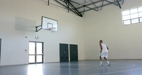 African American man practices basketball in a gym, with copy space