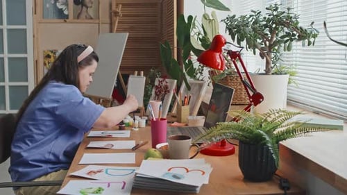 Young Adult Painting Watercolors at Desk