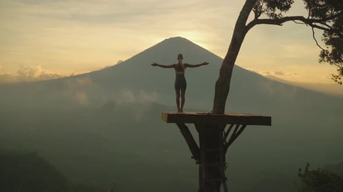 Mulher esticando e estendendo os braços enquanto olha para o Monte Agung durante o pôr do sol, Lahangan Sweet