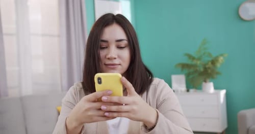 Woman Using Phone Indoors in Cozy Home Setting