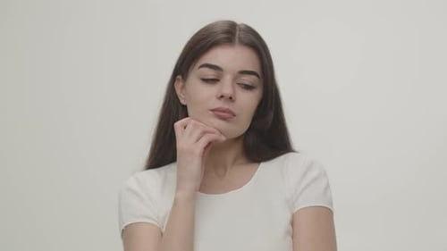 Beautiful Girl Looks Thoughtfully Into the Camera Trying to Figure Out How to Solve the Problem