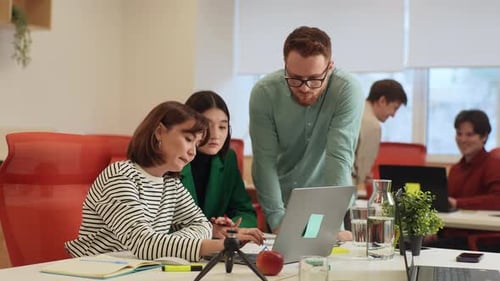 Diverse Team Collaborates on Laptop Project in Bright Office