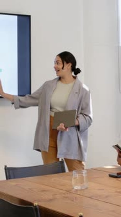 Vertical video: Diverse coworkers presenting upon tablet handoff while comparing graph in boardroom