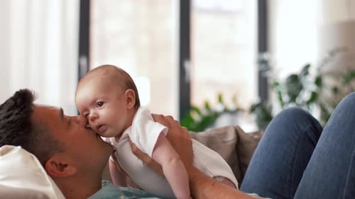 Loving Father Holds Baby in the Air Indoors