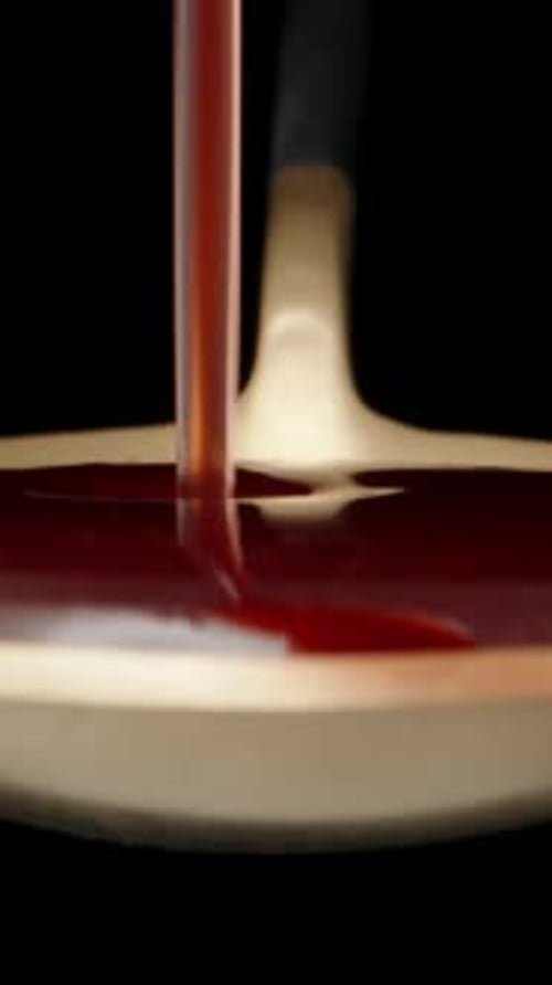 I pour red syrup on a golden spoon. Dolly slider extreme close-up. Laowa Probe Vertical video.