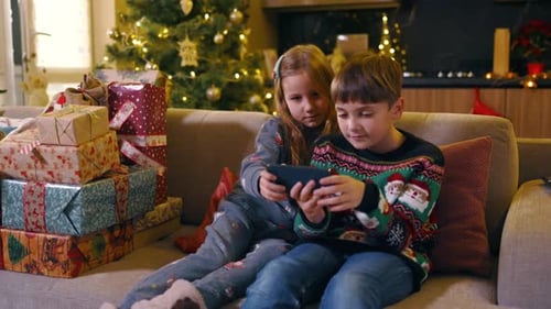Children Playing on Phone With Christmas Presents