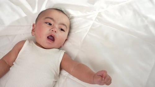 Happy Infant Smiling on White Blanket