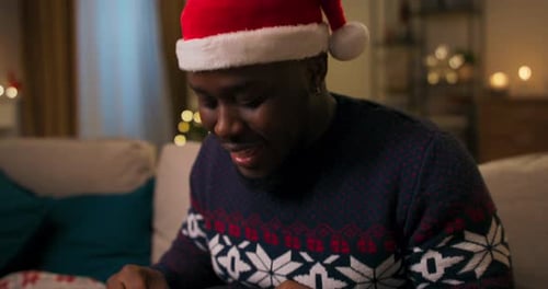 Man Joyfully Opening Christmas Gift at Home