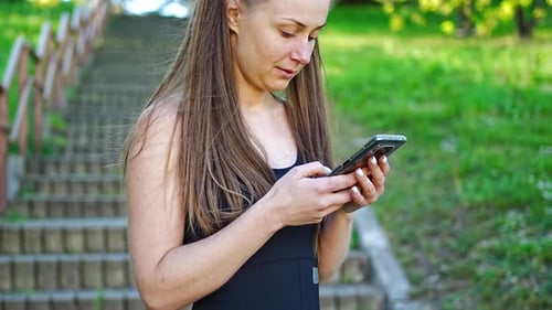 Woman Uses Smartphone Outdoors by Stairs