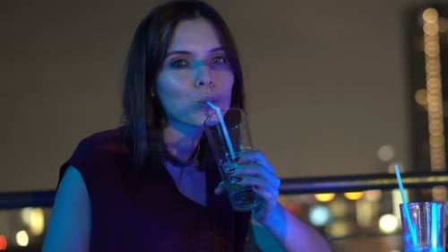 Portrait of Happy Woman Drinking and Raising Toast on Terrace in Bar