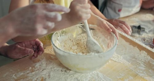 Close Up Shot Selective Focus Kid's Small Hands Trying to Mix Homemade Dough with Flour Using Big