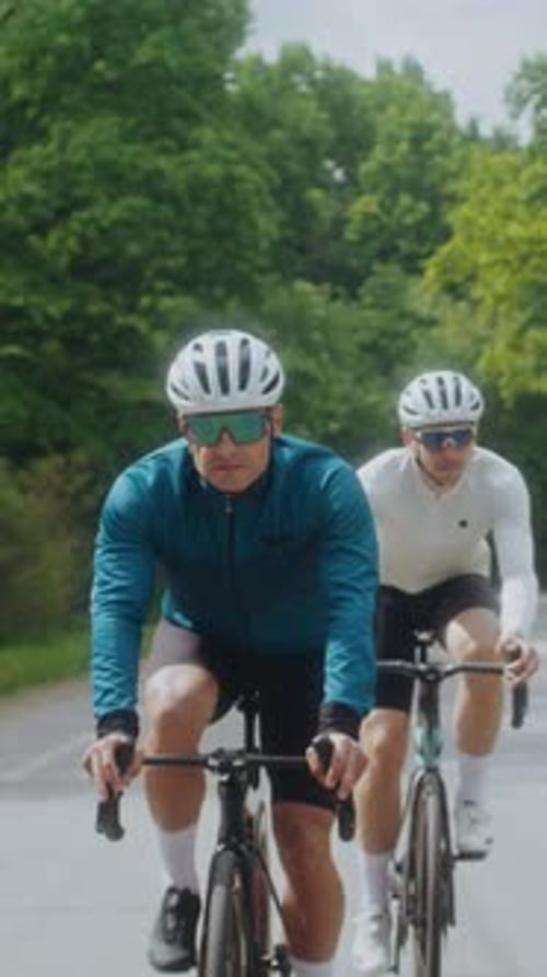 Rennführer in Schutzhelmen fahren mit dem Fahrrad auf der Asphaltstraße