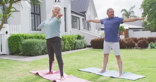 Happy senior diverse couple practicing yoga in garden