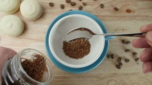 Adding Instant Coffee to Cup with Spoon Close Up