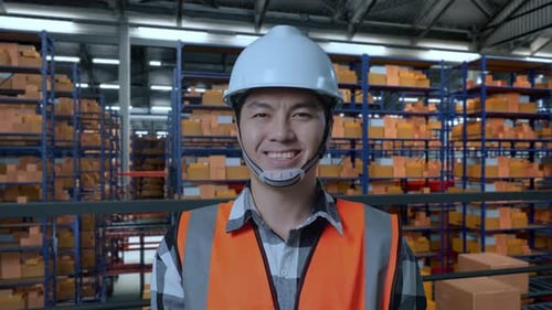 Asian Male Engineer Smiling To Camera While Standing In The Warehouse