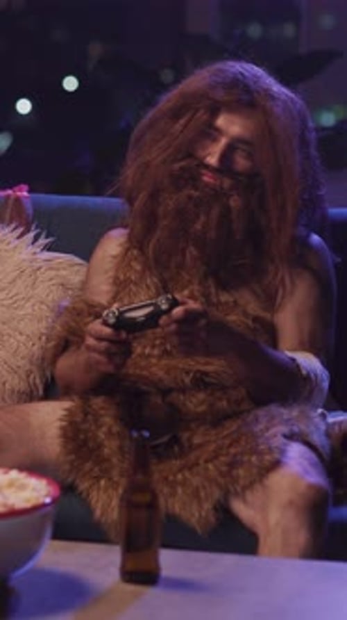 Bearded Ancient Savage Man in Furry Animal Leather Clothes Falling Asleep After Playing Videogames