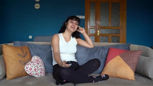 Woman Relaxing on Sofa with Remote Control