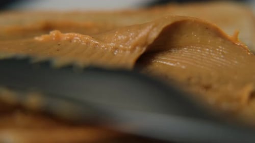 Spreading Peanut Butter on Bread with Knife Close-up