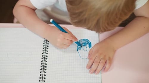Child Draws in Notebook with Blue Marker