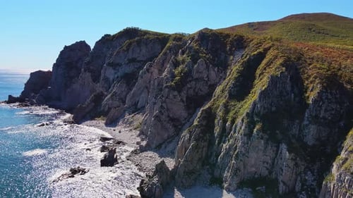 A Rocky Cliff Above the Sea with Waves Breaking on the Shore