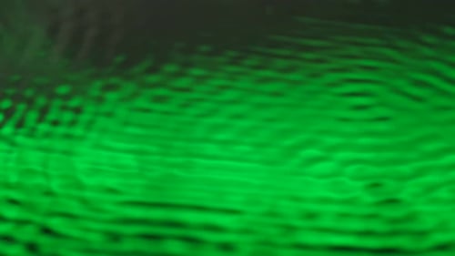 Water with Beautiful Green Neon Light Creating Ripples Under Ultra Sound Vibrations Abstract