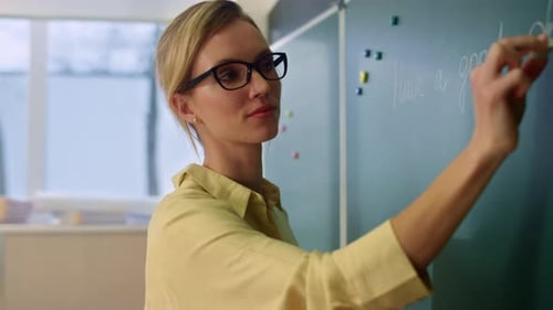 Teacher Writing on Chalkboard in Classroom Setting