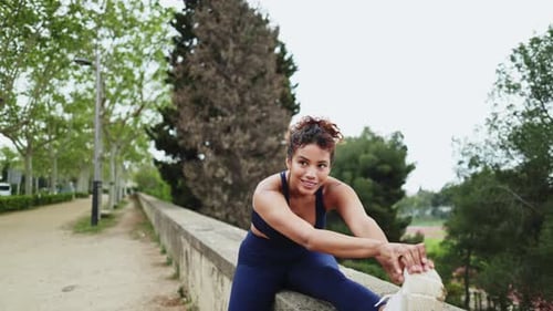Young Sportswoman Stretching Legs in a Park